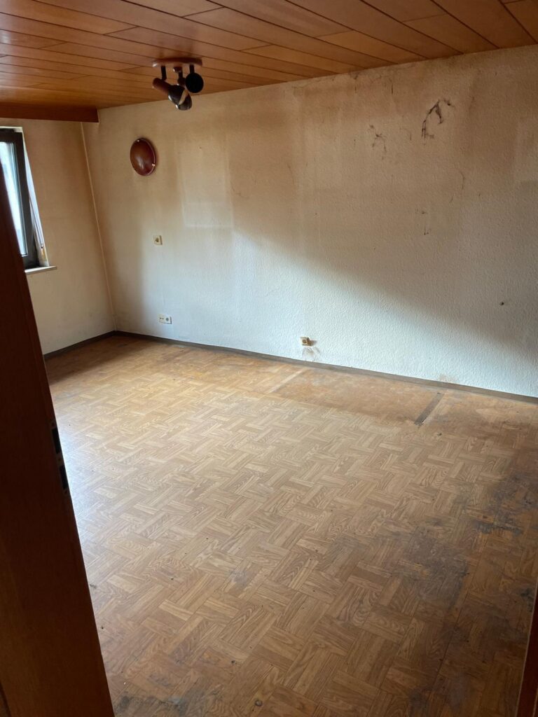 Leeres Zimmer mit Holzdecke und Parkett nach der Entrümpelung