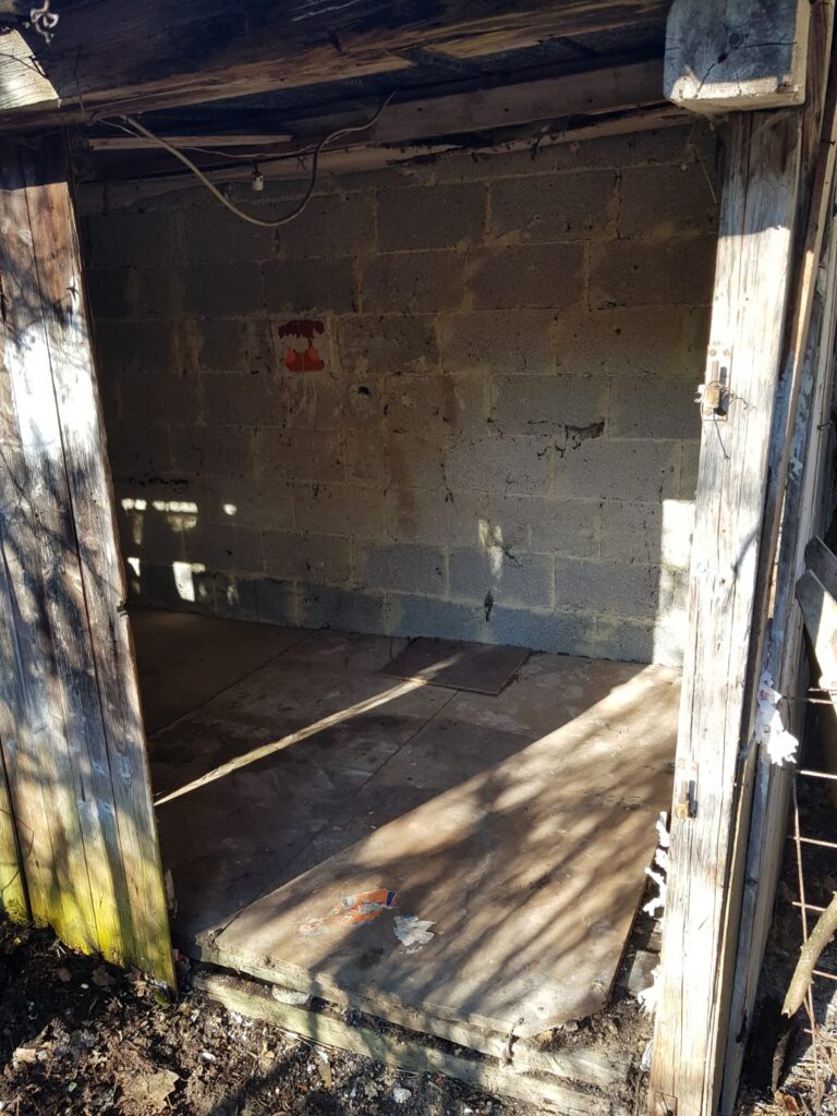Geräumter Schuppen mit Betonsteinwand nach der Entrümpelung