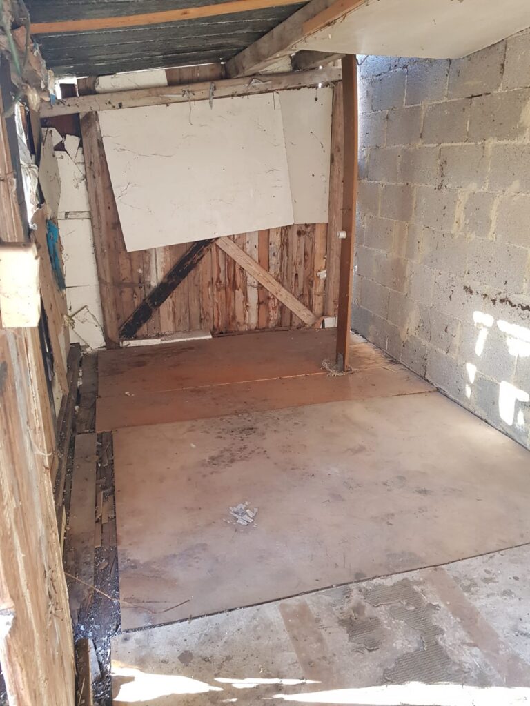 Leerer Holzschuppen mit Bretterboden nach der Räumung