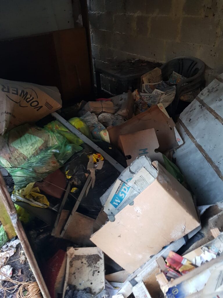 Holzschuppen voller Kartons, Säcke und Sperrmüll vor der Entrümpelung